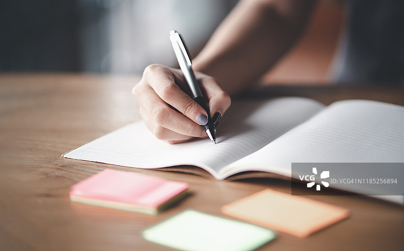 女商人在办公室办公桌前工作，手持文件记录笔记图片素材