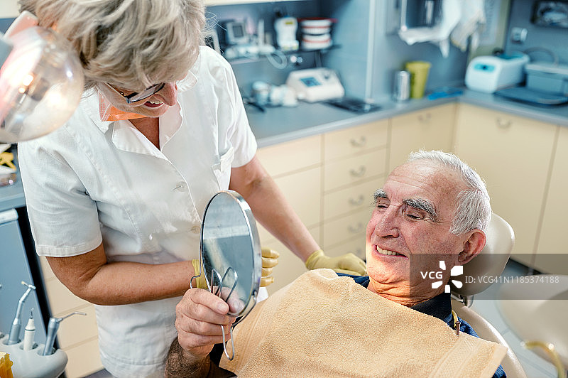 老年男人在牙科诊所欣赏她的笑容图片素材