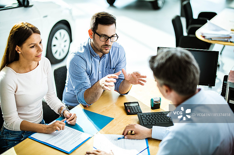情侣在汽车展厅的会议上与销售人员交谈图片素材