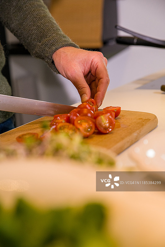 男性在厨房用刀切番茄特写图片素材