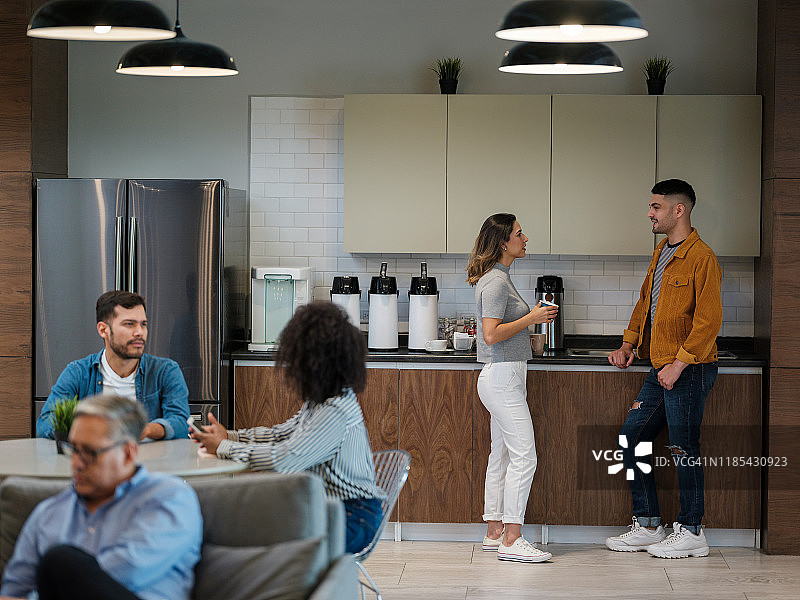 在公司午餐室喝咖啡聊天的拉丁裔青年图片素材