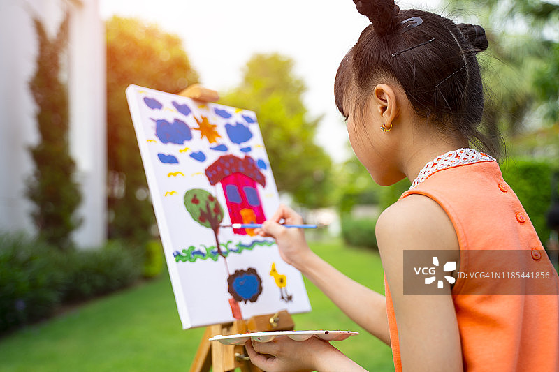 在花园里用画架绘画的小女孩图片素材