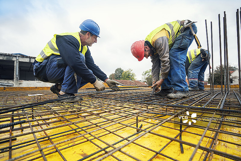 工人在建筑工地将绑线安装到钢筋上图片素材
