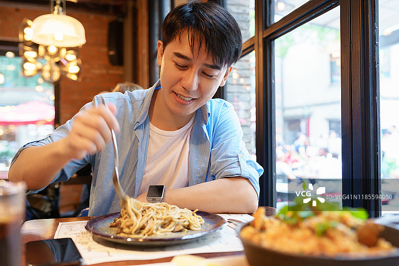 年轻的亚洲男子吃面条图片素材