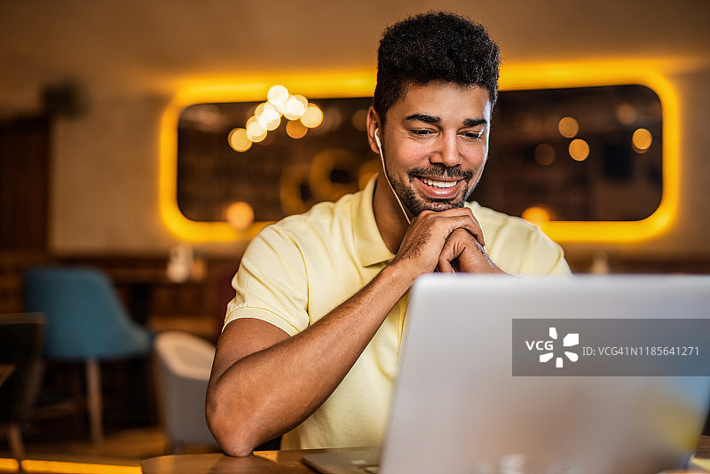 快乐的男人在咖啡店看播客图片素材