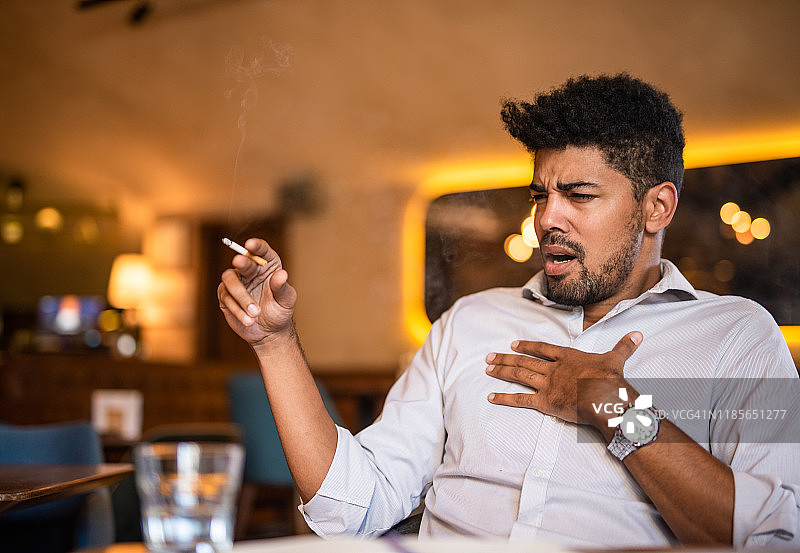 中年男人在酒吧抽烟并咳嗽图片素材