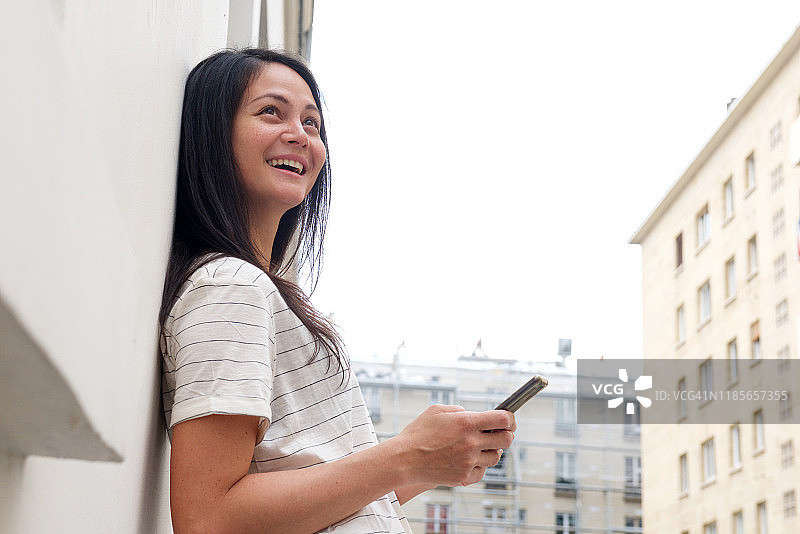 快乐的亚洲年轻女人在城市里拿着手机图片素材