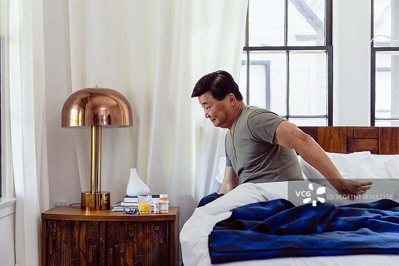 年长的男人醒来后坐在床边图片素材