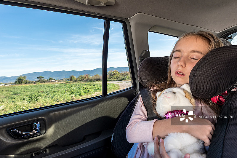 公路旅行中在汽车座椅上睡觉的可爱女孩图片素材