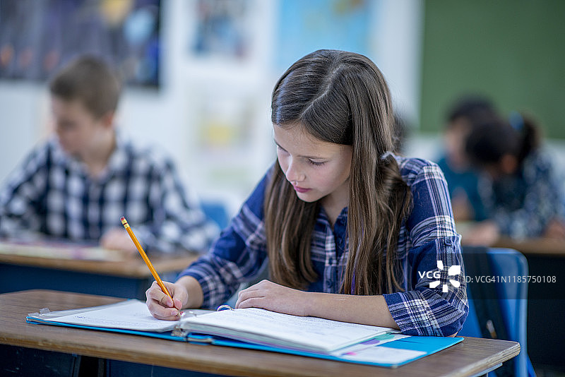 坐在书桌前写作的年轻小学生 - 高清图片图片素材