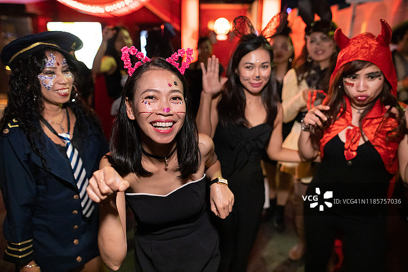 万圣节服装的亚洲女性朋友在夜晚的街道上行走跳舞图片素材