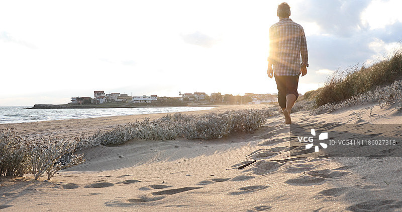 日出时分走在海边沙丘上的中年男人图片素材