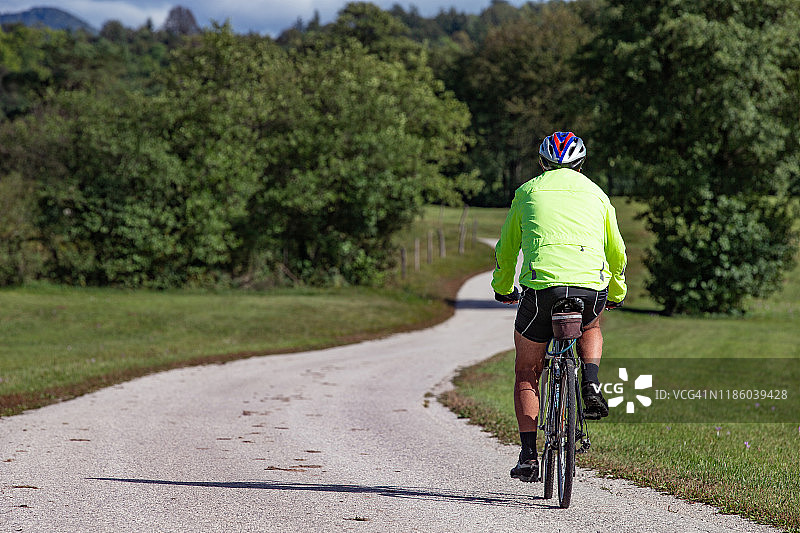 成年男人独自在乡村道路上骑行图片素材