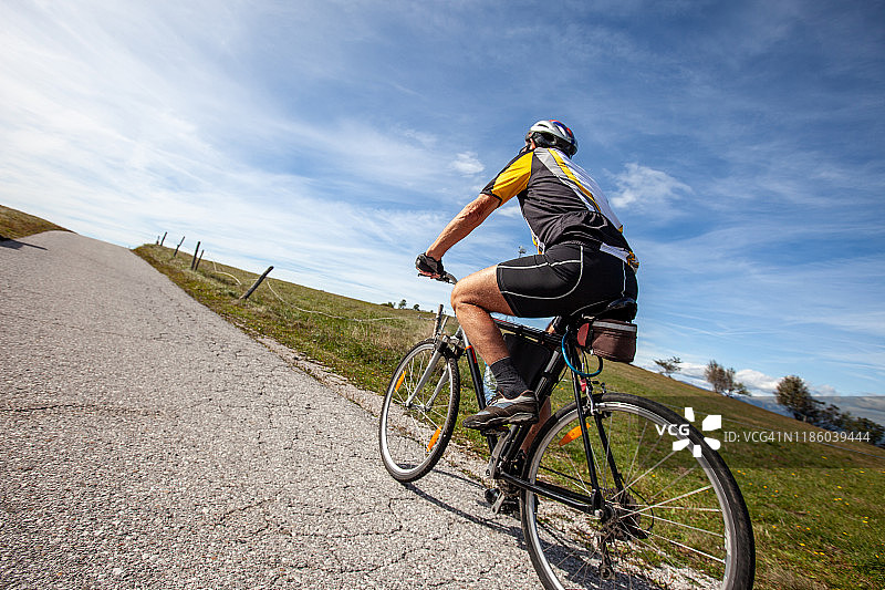 年长的男人在乡村道路上骑自行车图片素材