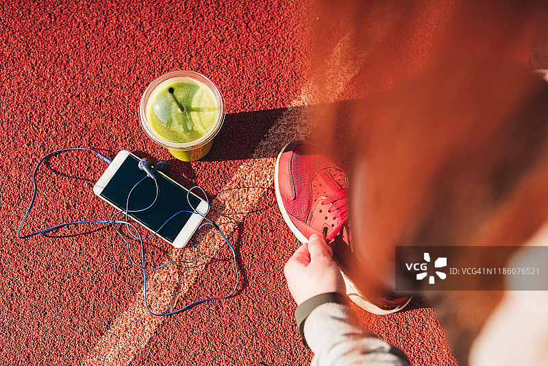 在体育场上系鞋带的女人图片素材