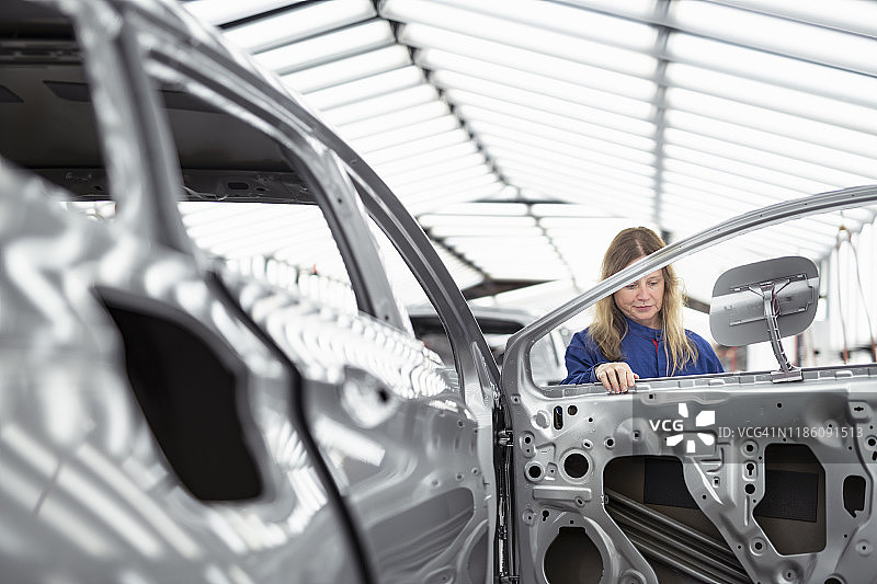 汽车工厂油漆检验区内检查车身的工人图片素材