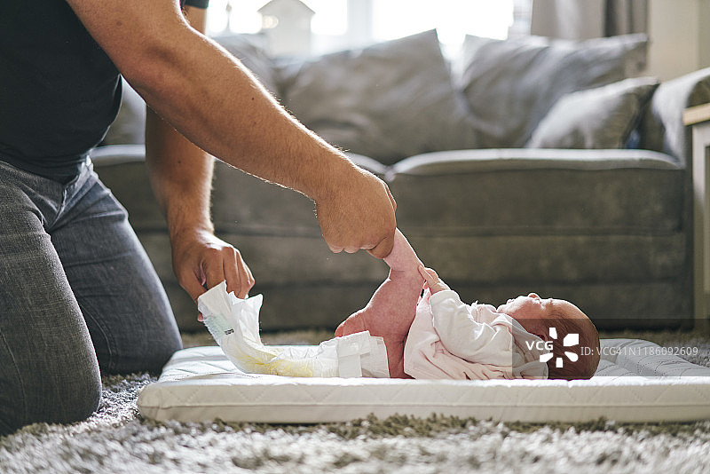 父亲在家为宝宝换尿布图片素材