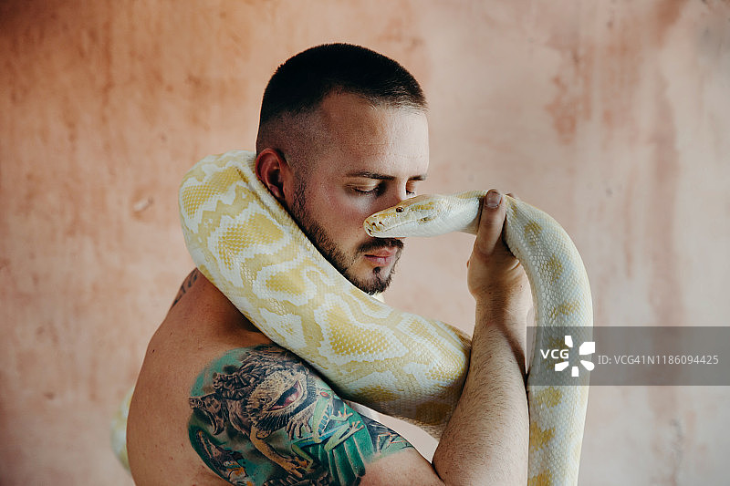 男人拿着蟒蛇靠近脸部图片素材
