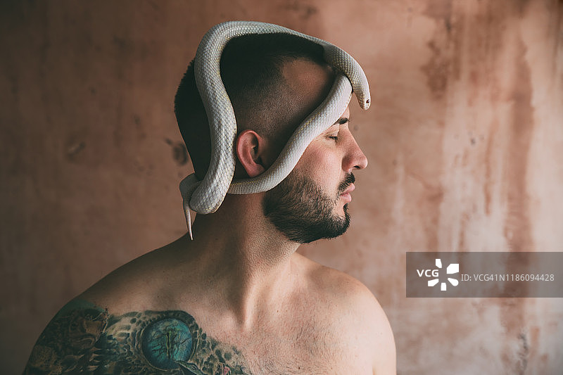 闭着眼睛头上盘着蛇的男人图片素材