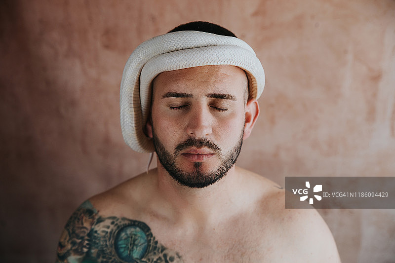 闭着眼睛头上盘着蛇的男人图片素材