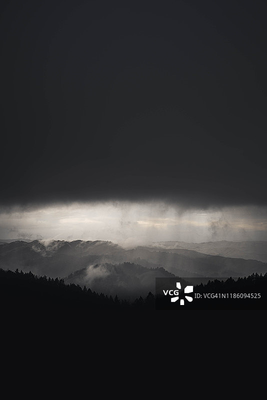 山丘和森林上空的深色风暴云图片素材