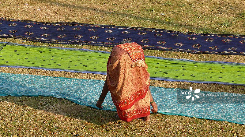 在印度卡纳塔克邦亨比，妇女在阳光下晾晒传统纱丽图片素材