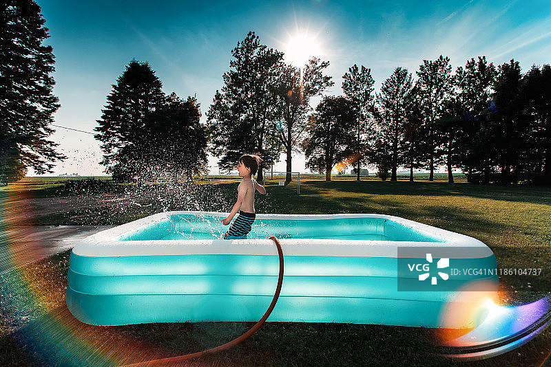 在阳光下于游泳池里戏水的小男孩图片素材