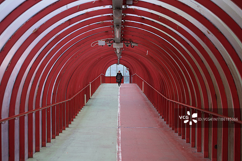 女人走在英国苏格兰格拉斯哥克莱德河上的有盖走道桥中间图片素材