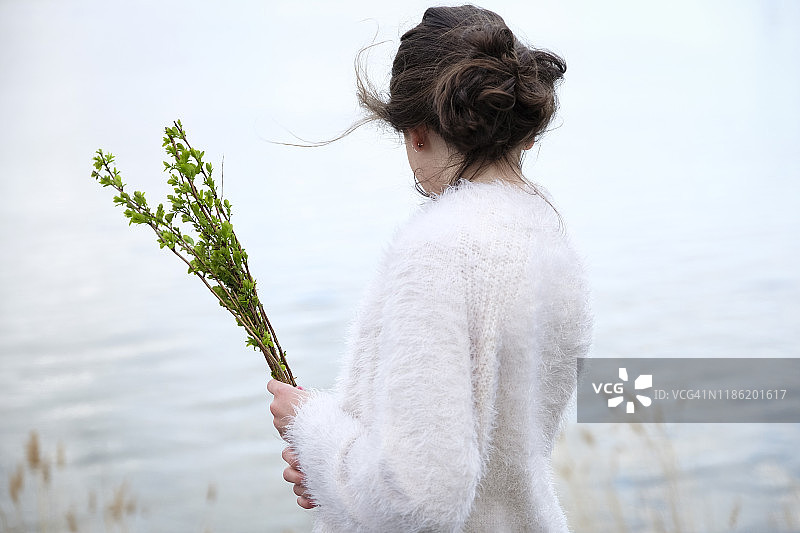 站在湖边手捧植物的女子侧视图图片素材