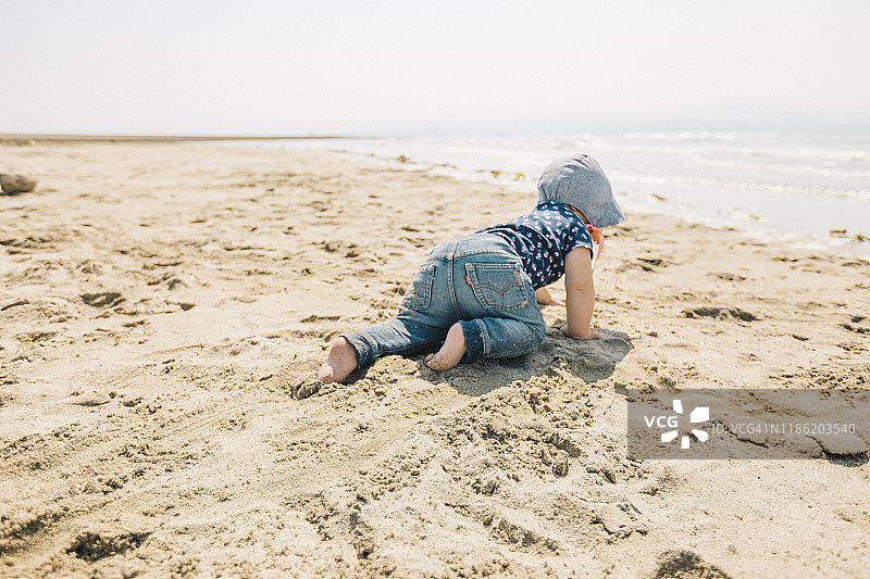 女婴在海滩上爬行图片素材