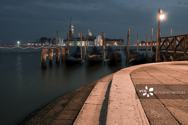 波浪上的贡多拉和圣乔治马焦雷岛的傍晚景色图片素材