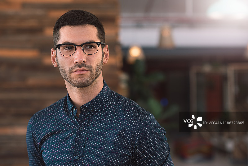 专注的年轻商人在现代办公室里独自站立图片素材