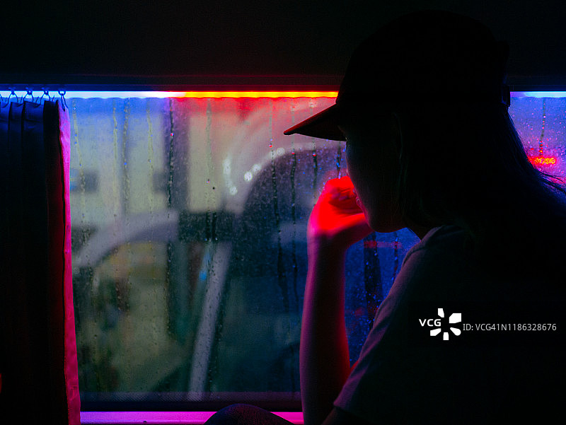 夜晚，女子隔着玻璃向外看图片素材
