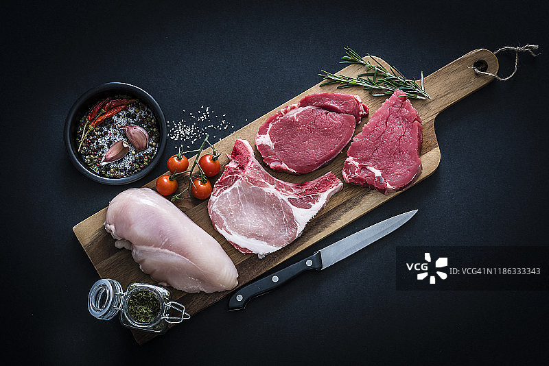 生肉拼盘 - 牛肉、鸡肉和猪排，深色背景俯视拍摄图片素材