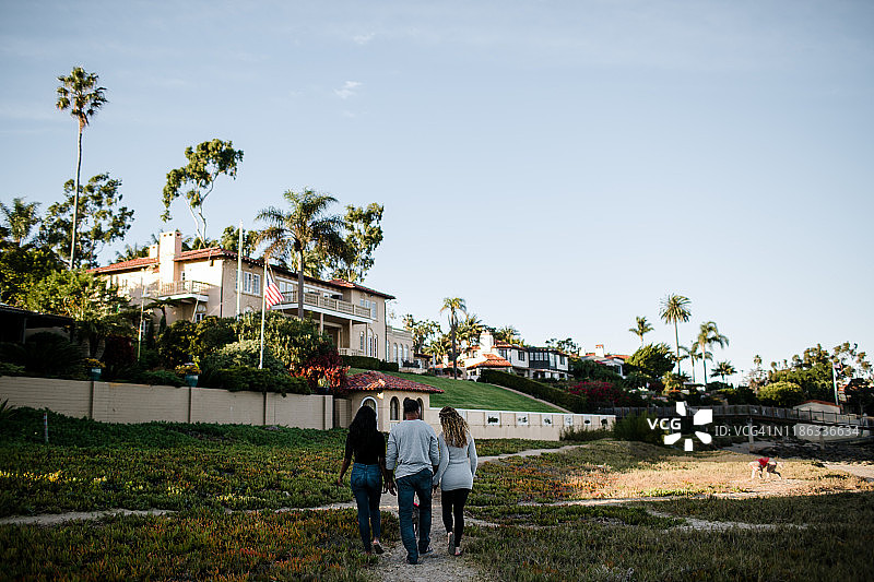 重组家庭在日落时分的海滩小径上散步图片素材