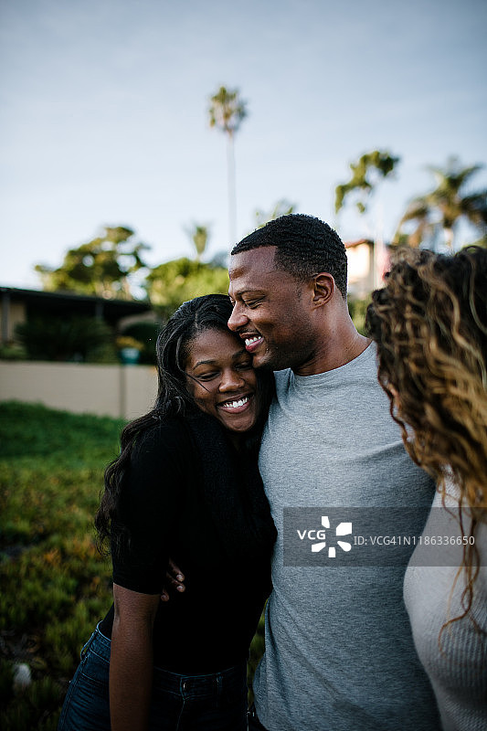 父亲拥抱女儿，继母在海滩上看着图片素材