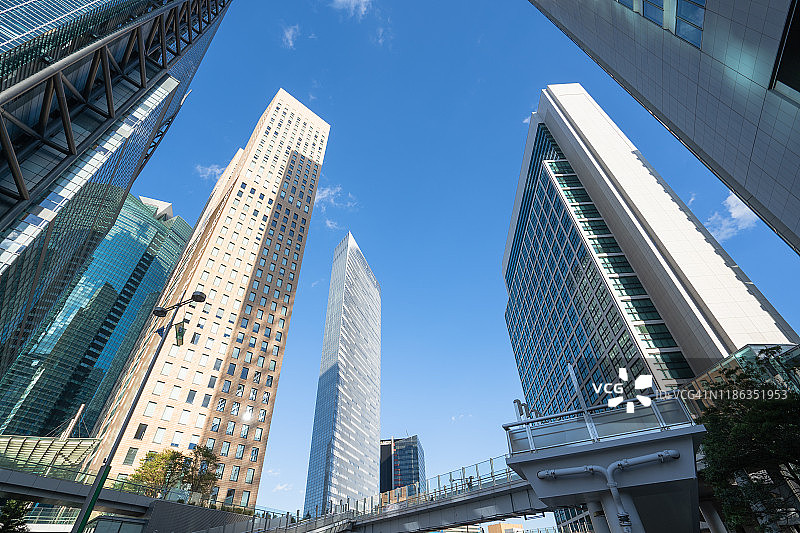 日本城市景观：仰望蓝天下由玻璃和钢铁构成的现代建筑图片素材