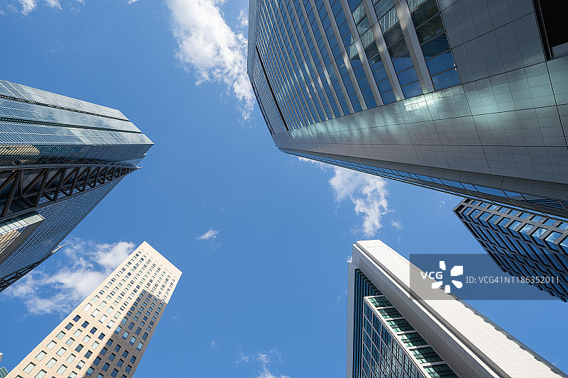 日本城市景观：仰望蓝天下由玻璃和钢铁构成的现代建筑图片素材