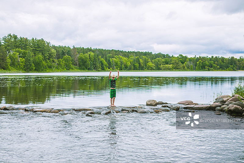 男孩在过河石时欢呼图片素材