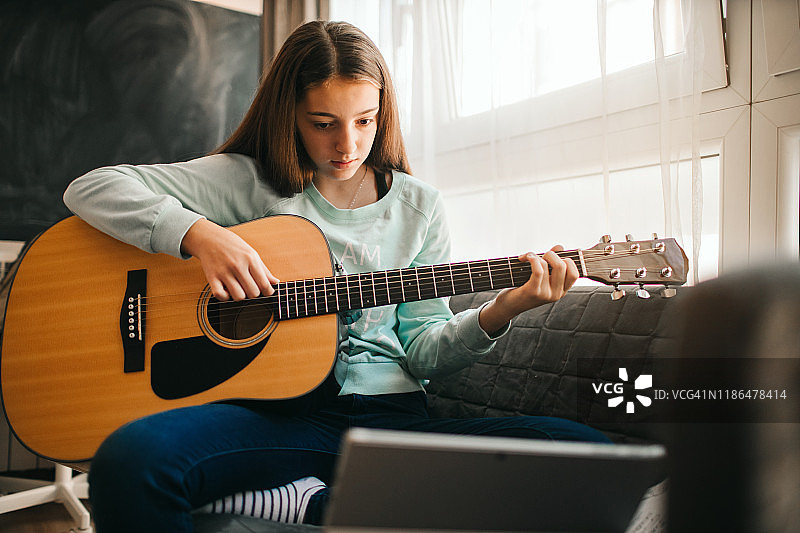 可爱的青少年女孩在线学习弹吉他图片素材