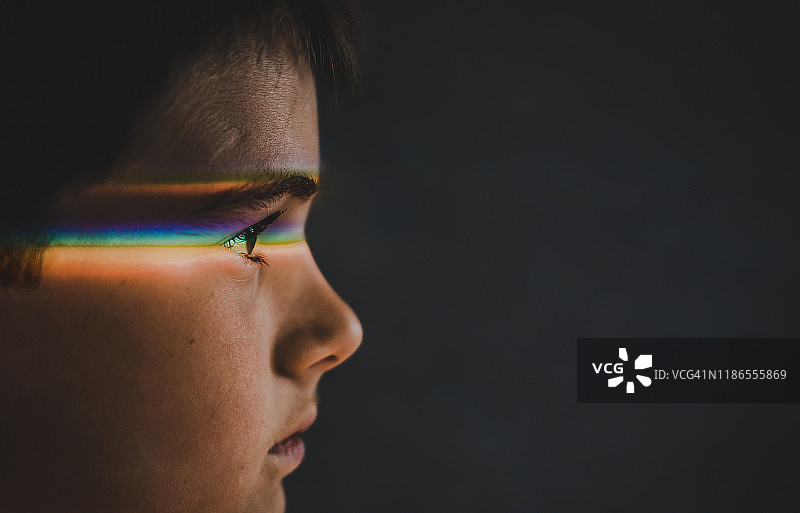 若有所思的男孩眼睛在黑色背景下的光谱特写图片素材