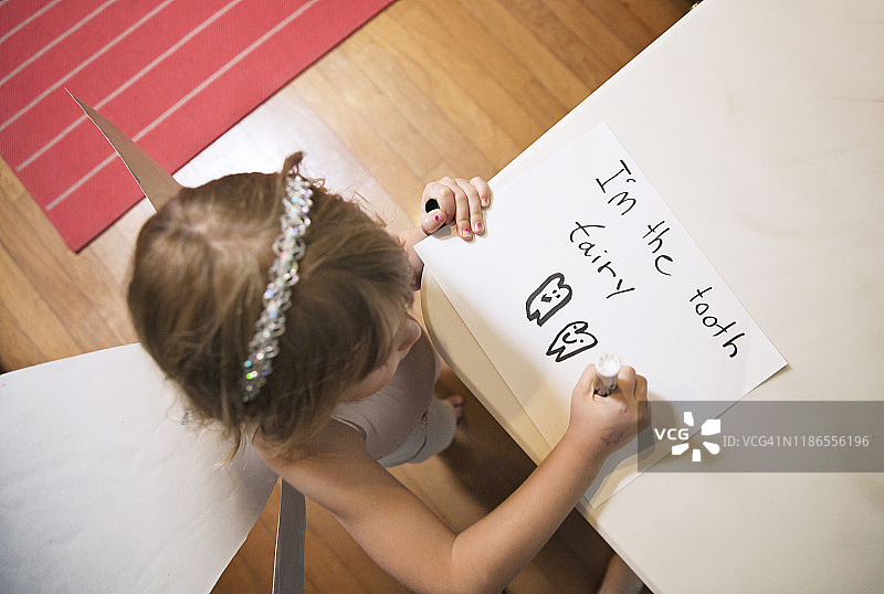 女孩在家穿着牙仙服装写字图片素材