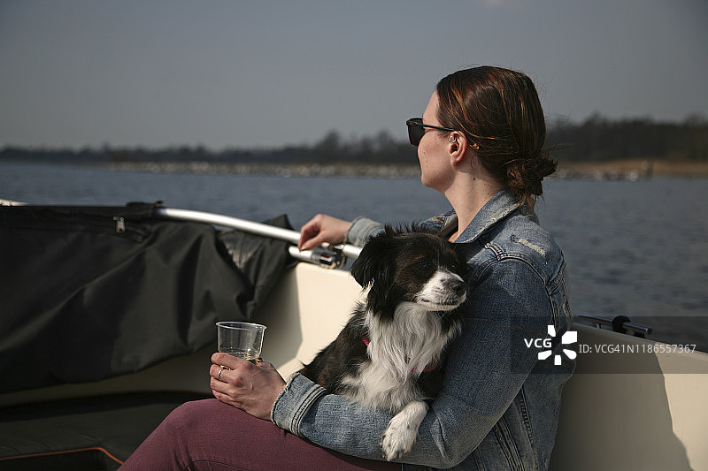年轻的白人女性在船上和小狗一起放松图片素材
