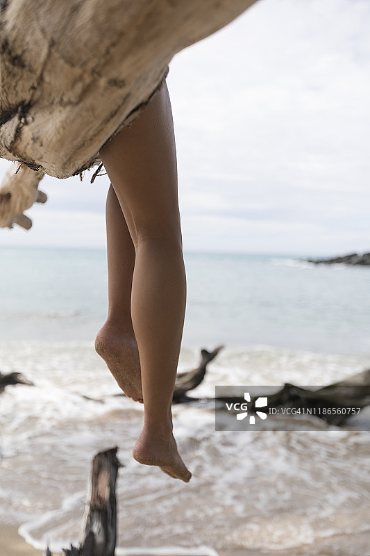 坐在海边树枝上的女人的下半身图片素材
