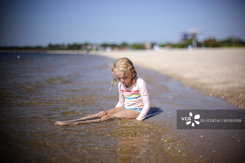 在纽约萨格港海滩水边坐着的金发女孩图片素材