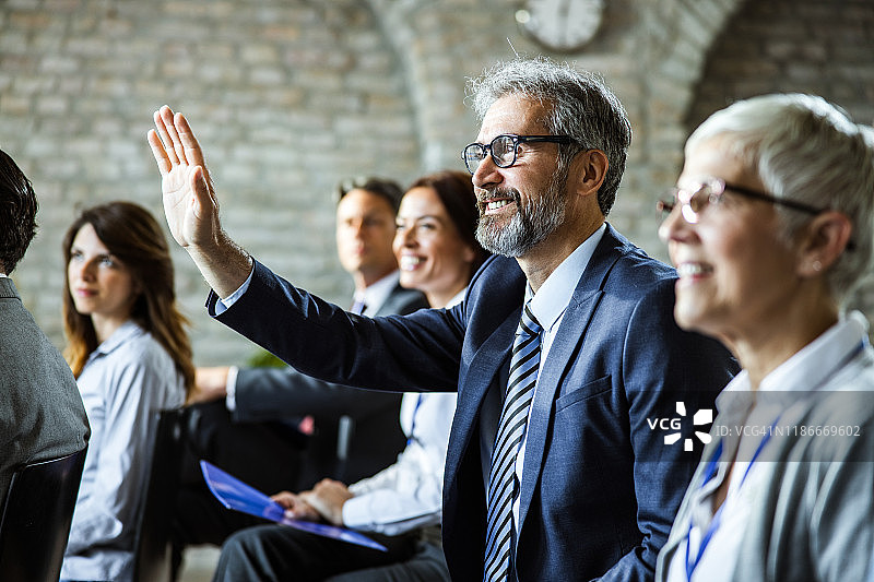 在研讨会上提问的快乐中年商人图片素材