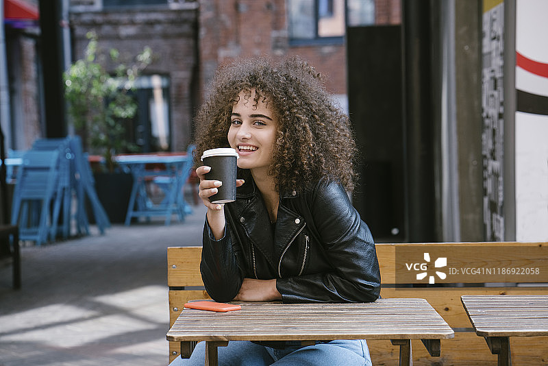 坐在长椅上喝咖啡的微笑少女肖像图片素材