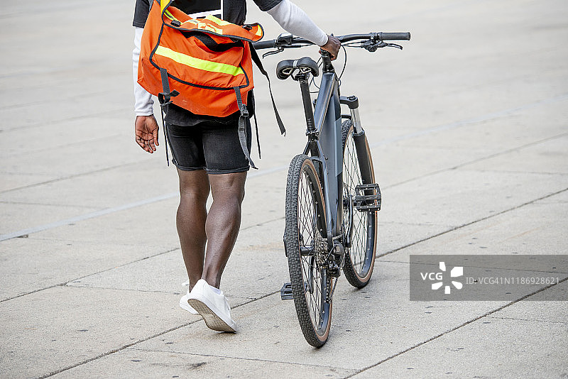 背着邮差包推自行车的年轻男人图片素材