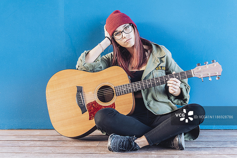 坐在木地板上弹吉他的少女图片素材
