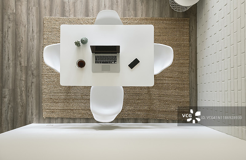 白色桌子，笔记本电脑，智能手机和一杯咖啡在现代阁楼里，从上方看图片素材